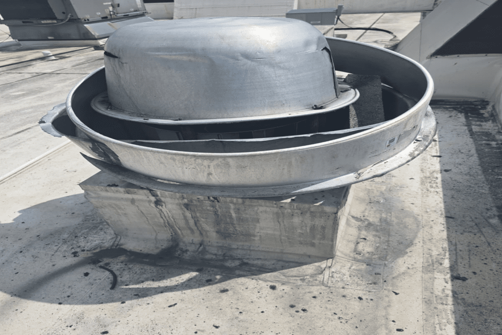 Before: Severely damaged rooftop exhaust fan — grease buildup, corrosion, and structural failure evident