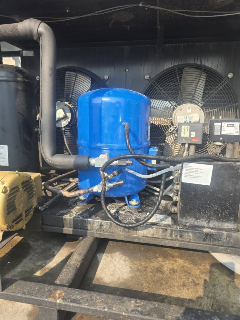 Close-up of the compressor assembly, condenser fans, and refrigerant lines during the commercial chiller repair inspection.