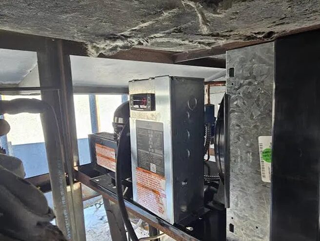 Control panel and electrical components inside the walk-in cooler's condensing unit housing.