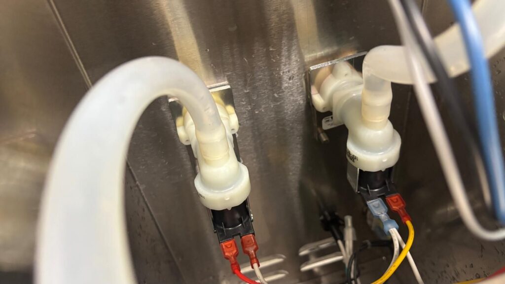Dual solenoid water inlet valves mounted inside the brewer cabinet, with wiring connectors visible.